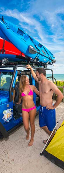 Couple leaning on blue Jeep at the beach